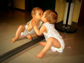 Cute girl kissing her reflection in mirror at home