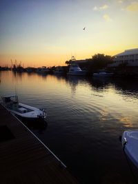 Sailboats moored in lake against sky during sunset