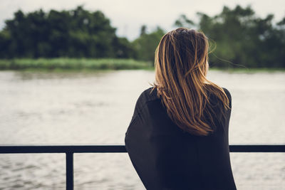 Rear view of woman standing by sea against sky