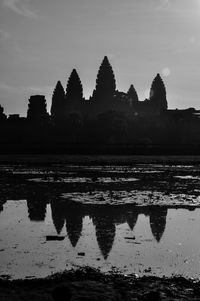 Reflection of silhouette trees in lake against sky
