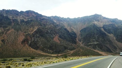 Scenic view of road by mountains against sky