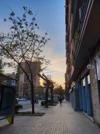 People on street amidst buildings in city during sunset