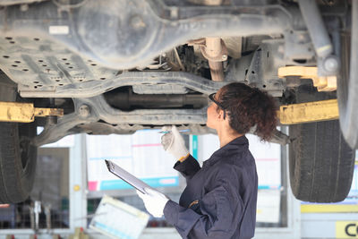 Woman examining car in garage