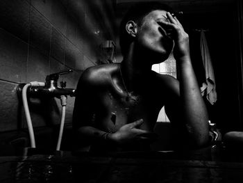 Young man sitting in bathroom