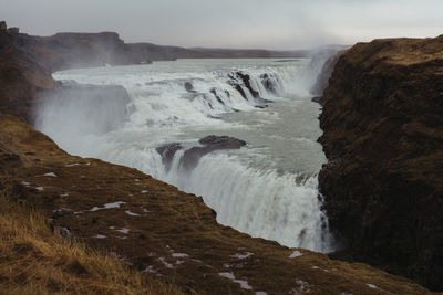 Scenic view of waterfall against sky