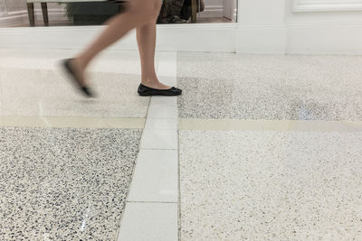Low section of woman walking on tiled floor