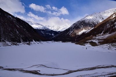 Scenic view of snow covered mountains against cloudy sky