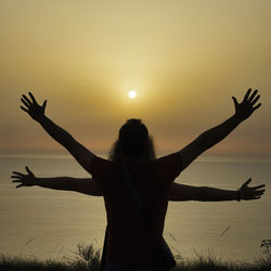 Silhouette woman with arms outstretched against sky during sunset