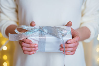 Female hands hold christmas or new year gift box on boke background. christmas