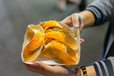 Cropped hands of woman holding tacos