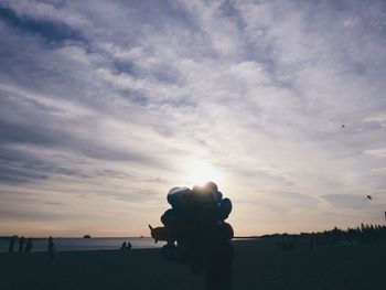 Silhouette people photographing sea against sky during sunset