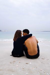 Rear view of couple sitting at beach