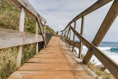 View of wooden footbridge leading towards sea