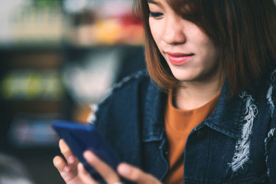 Close-up of woman using phone while sitting defocused background