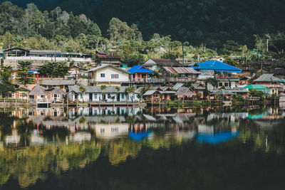 Houses by lake and buildings in city