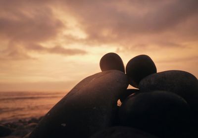 Low section of silhouette person on beach against sky during sunset