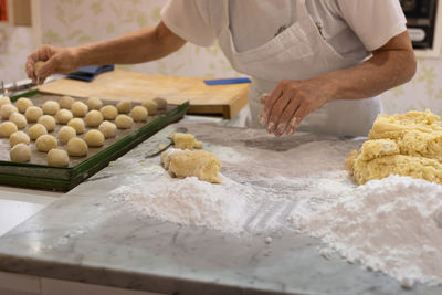 Working with hands of uncooked dough with flour and eggs for making round cakes.