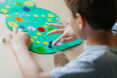 Child rolls the dice and moves the chip across the christmas playing field.