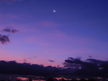 Low angle view of silhouette moon against blue sky at sunset