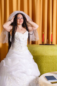 Young woman looking away while standing against curtain