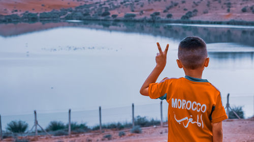 Rear view of boy standing by water