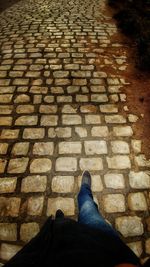 Low section of man standing on cobblestone street