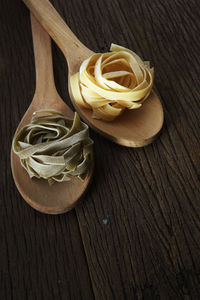 Close-up of tagliatelle pasta in wooden spoons on table