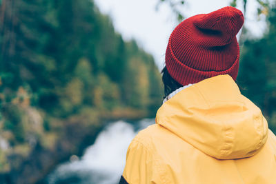 One with nature. back view of unrecognizable woman looking to forest and waterfall, female in bright 