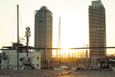 Construction site by buildings against sky during sunset
