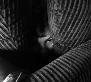 Close-up portrait of boy hiding amidst cushions on sofa