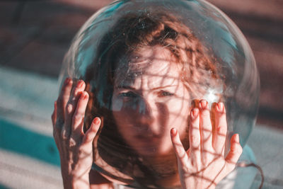 Close-up of young woman wearing glass container outdoors