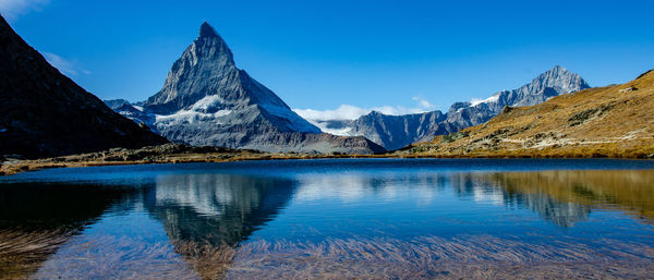 Scenic view of lake and mountains against blue sky