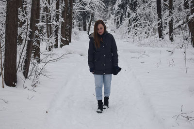 Full length of woman standing on snow covered field