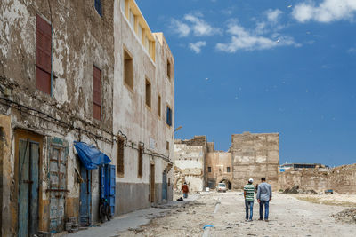 Men walking on footpath by old buildings in town