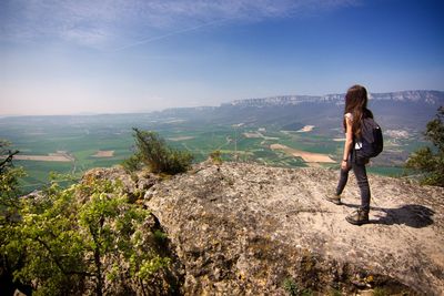 Woman standing on mountain while looking at landscape against sky