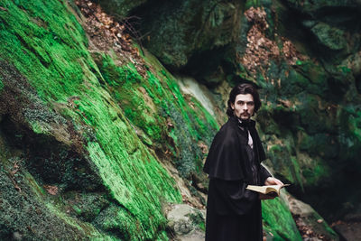 Young man in period costume standing by rocks