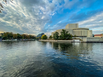 River by buildings in city against sky