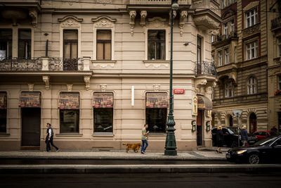 People on road by building in city