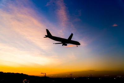 Low angle view of silhouette airplane flying against sky during sunset