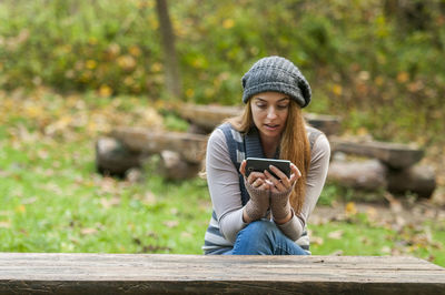 Young woman using mobile phone while sitting in park