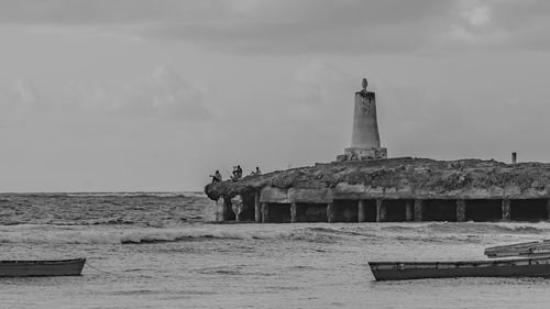 Lighthouse on beach against sky