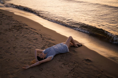 High angle view of boy lying on sand at beach