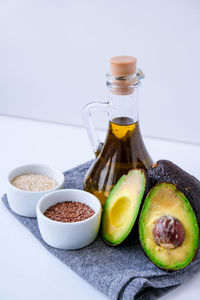 Olive oil in glass bottle with sesame and flax seeds. fresh ripe hass avocado. 