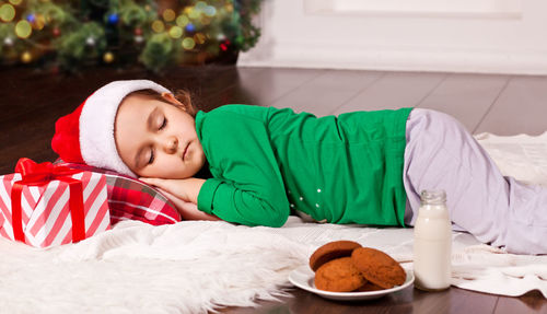 Cute girl wearing santa hat sleeping at home