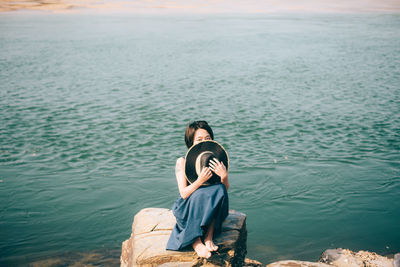 Woman sitting on rock at beach