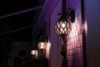 Close-up of illuminated lighting equipment against wall at night