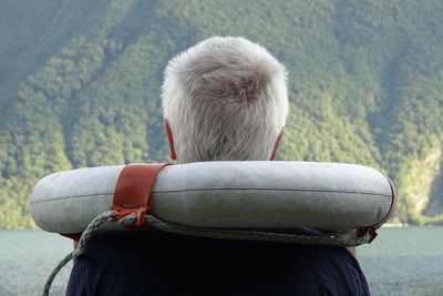 Rear view of man with life belt by river