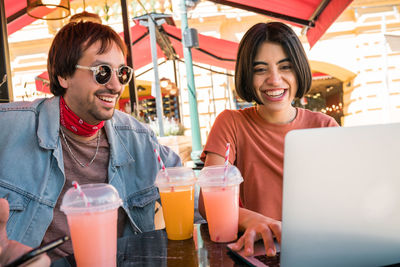 Portrait of smiling young woman drinking glasses at restaurant table