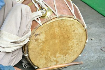 Low section of man sitting with drum