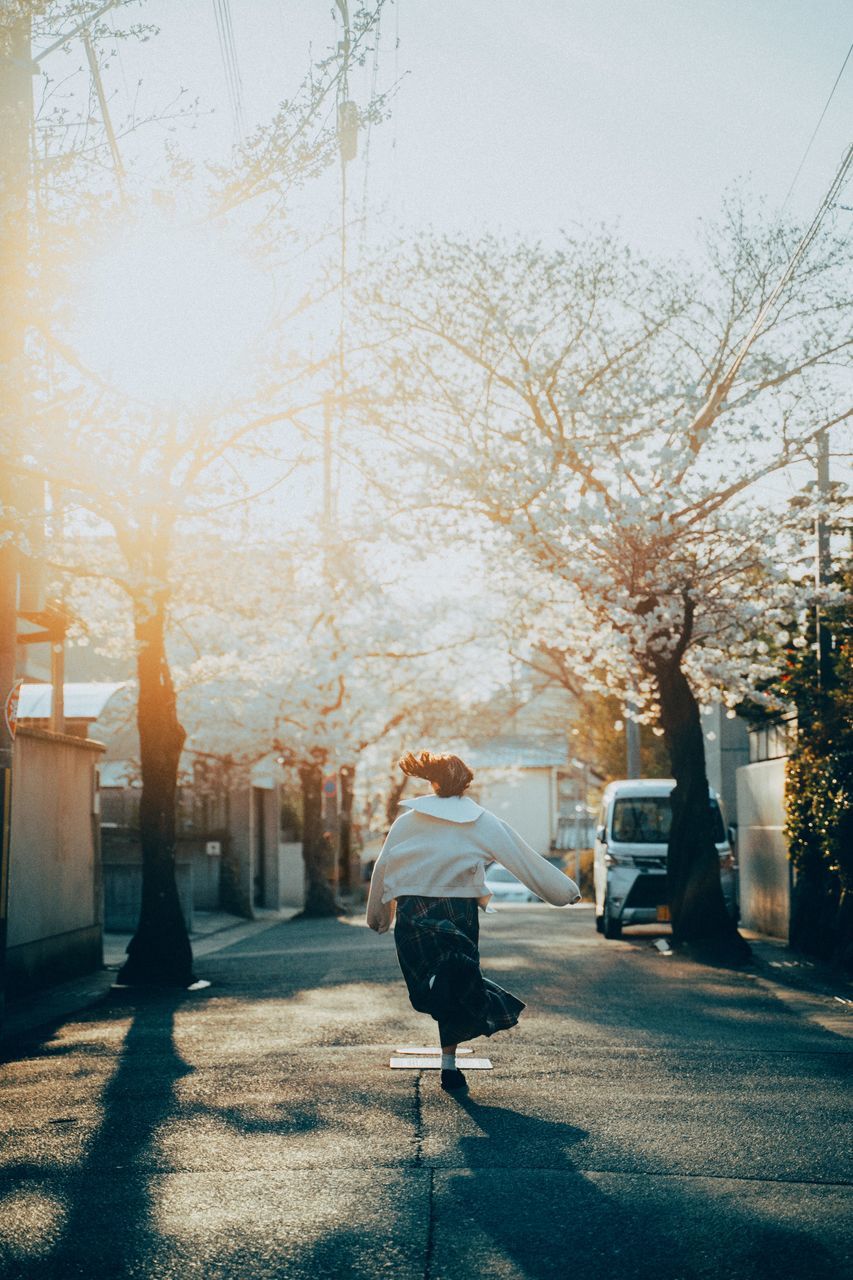 tree, morning, nature, city, plant, full length, sunlight, architecture, one person, transportation, adult, street, day, sky, rear view, road, building exterior, walking, men, outdoors, built structure, lifestyles, shadow, city life, women, winter, footpath, leisure activity, mode of transportation, motion, autumn, casual clothing, on the move, spring